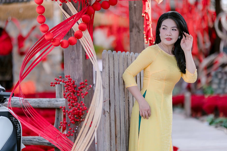 Woman in a yellow Ao Dai amidst festive red decorations, symbolizing celebration and culture.